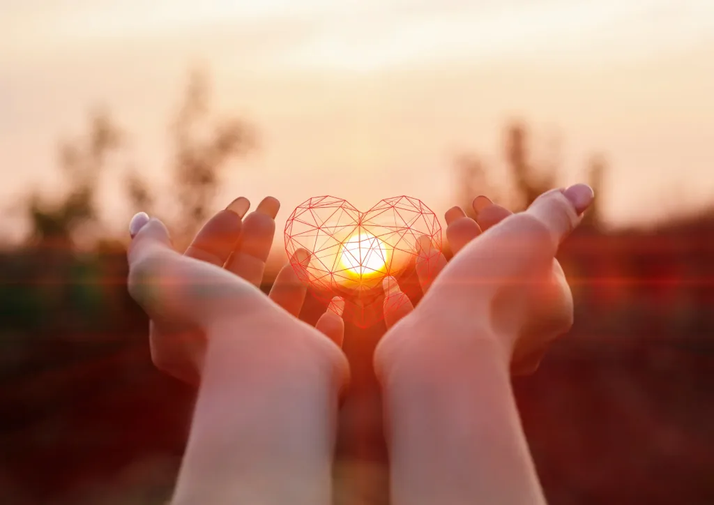 Hands gently holding a geometric heart shape with sunlight glowing behind, symbolising care, presence, and emotional support. After learning EQness techniques for stress managment and emotional overhelm.