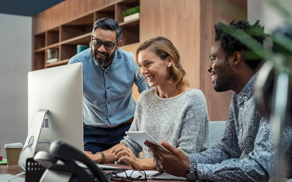 Three business people in front of a computer, showing harmony at EQness